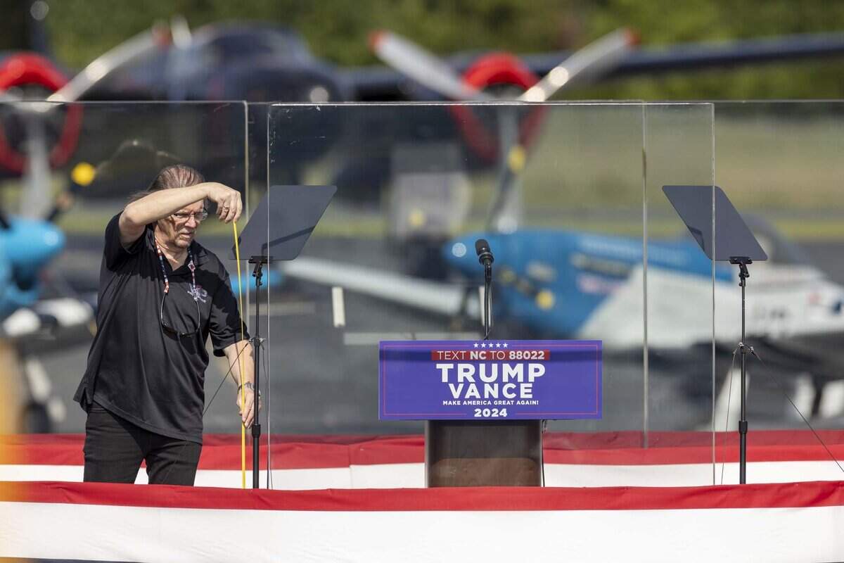 A campaign worker takes measurements behind bulletproof glass prior to an outdoor rally for former President Donald Trump and his running mate JD Vance at the North Carolina Aviation Museum & Hall of Fame in Asheboro, NC on Wednesday, Aug. 21, 2024.