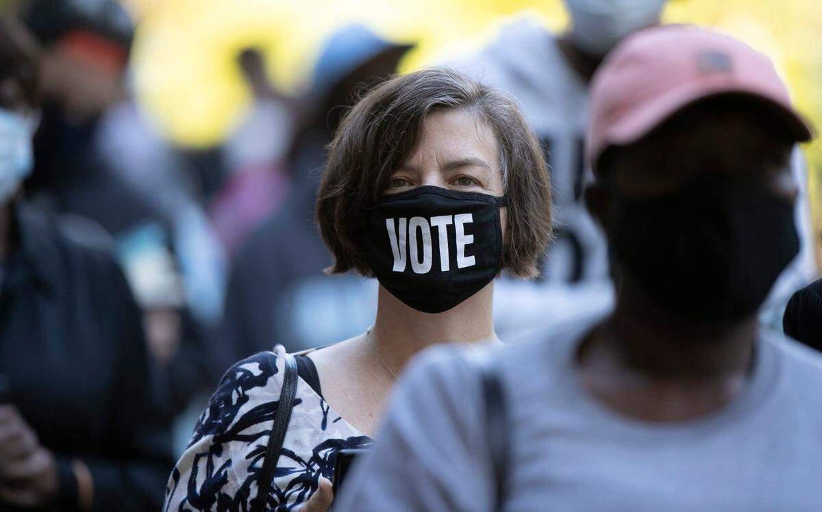 Holly Hurlburt sports her vote mask as she waits in line to vote with several hundred others at the Roberts Park early voting site on Thursday morning, October 15, 2020 in Raleigh, N.C.
