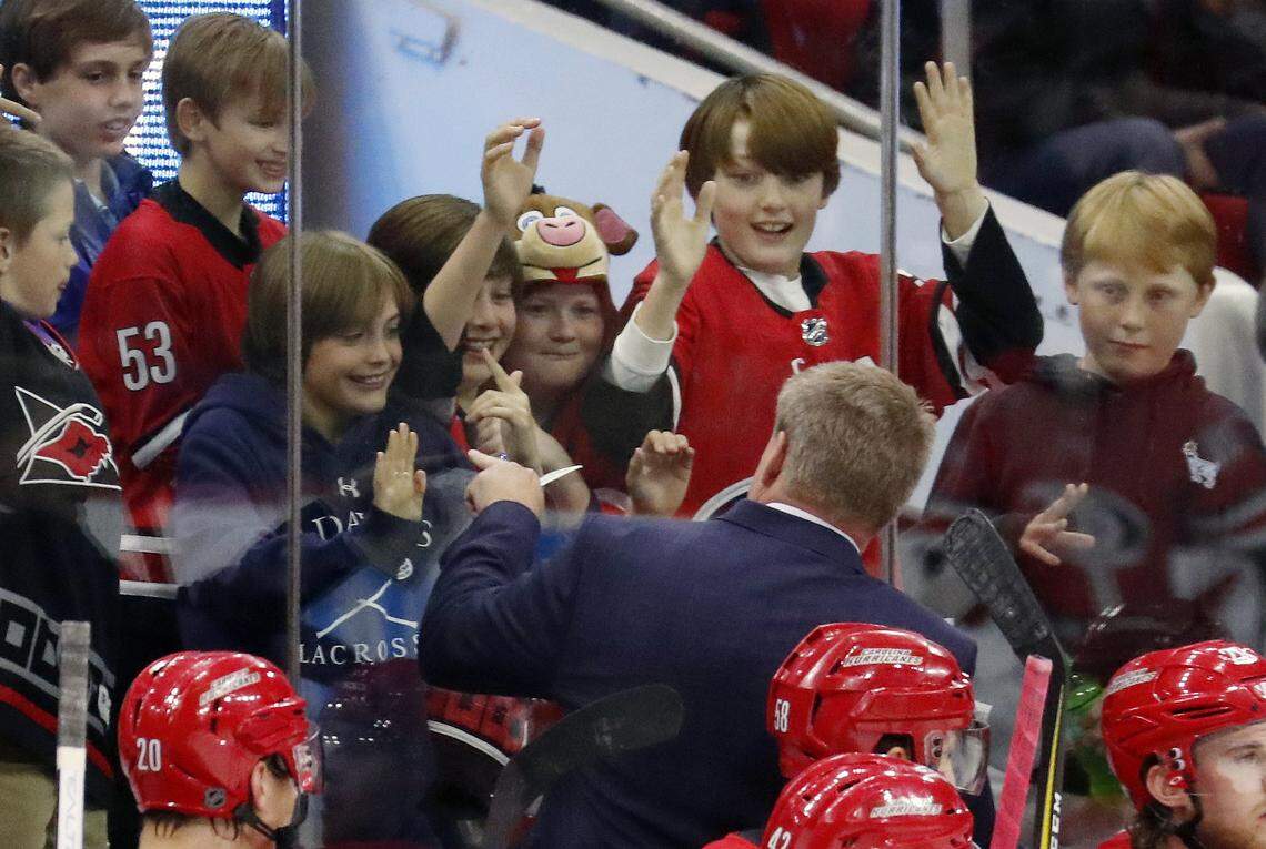In what proved to be his last game as head coach of the Carolina Hurricanes, Bill Peters interacts with young fans behind the bench during an NHL game played between the Carolina Hurricanes and the Tampa Bay Lightning at PNC Arena in Raleigh, N.C. on April 7, 2018. Peters recently resigned as head coach of the Canes and was named the new coach of the Calgary Flames on Monday, April 23rd.