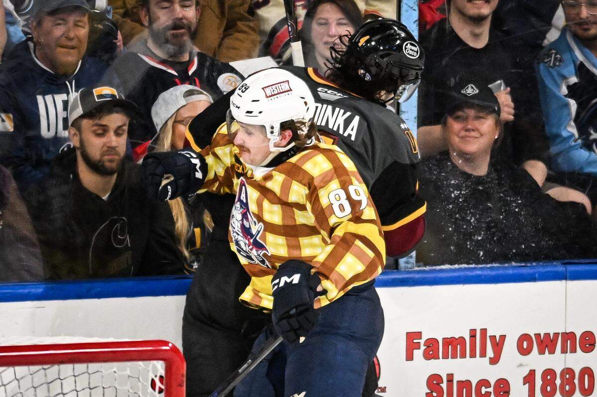 Milwaukee Admirals right wing Ozzy Wiesblatt (89) slams Chicago Wolves defenseman Dominik Badinka (4) into the boards in a game Friday, April 18, 2025, at the UW-Milwaukee Panther Arena in Milwaukee, Wisconsin.