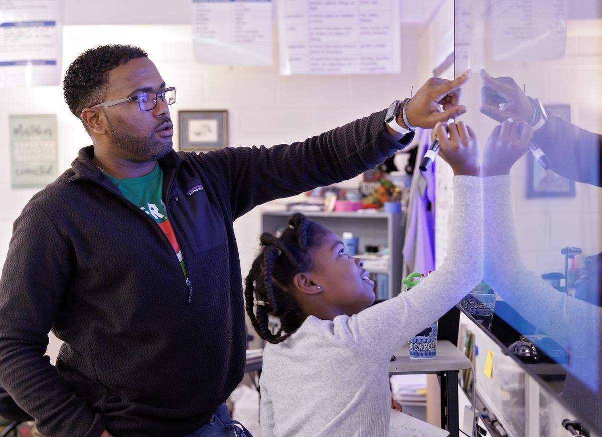 Pittsboro Elementary School fourth-grade teacher Shane Henderson, who recently won the Milken Educator Award, helps Nailah McMillan solve a problem during class. 
