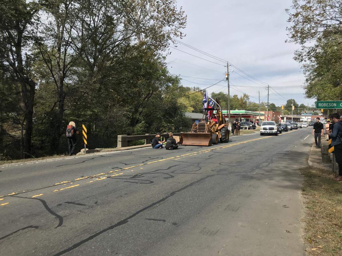 Protesters sit in front of a tractor flying a Confederate flag in Pittsboro on Oct. 19, 2019.