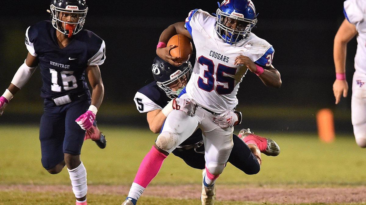 Wake Forest’s Chris Clark (35) runs for the first down against Heritage’s Foster Burt (5) during the second half. The Heritage Huskies and the Wake Forest Cougars met in a football game in Wake Forest, N.C. on October 15, 2021.