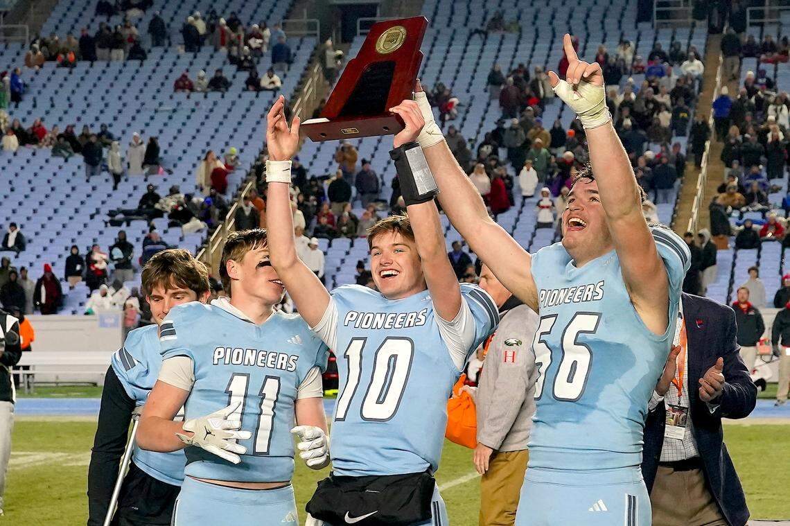 Watauga's Thomas Deiters (11), Cade Keller (10) and Brady C Lindenmuth (56) celebrate with the 6A football championship trophy after their defeat of Middle Creek on Dec. 12, 2025. 