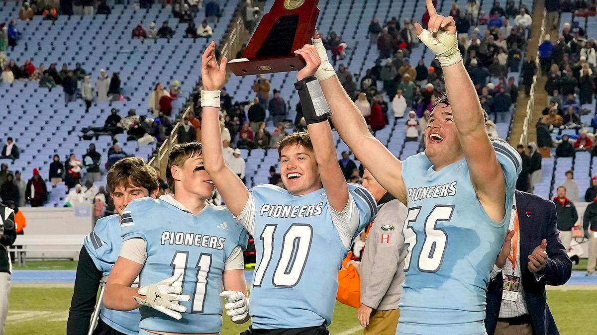 Watauga's Thomas Deiters (11), Cade Keller (10) and Brady C Lindenmuth (56) celebrate with the 6A Football Championship Trophy after their defeat of Middle Creek. The Middle Creek Mustangs and the Watauga Pioneers met in the NCHSAA 6A Football Championship game in Chapel Hill, N.C. on December 12, 2025. 