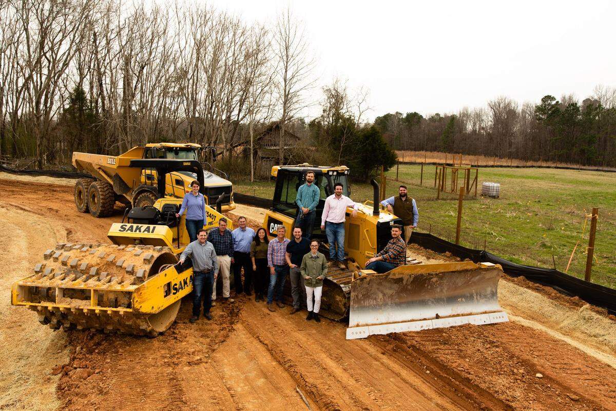 The team behind Wetrock Farm poses for a photo on the property of the future neighborhood. Rick Bagel, the driving force behind the project, is pictured third from the right.