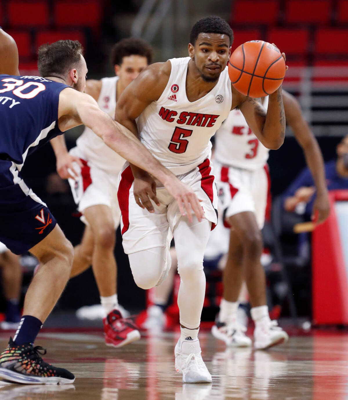 N.C. State’s Thomas Allen (5) brings the ball past Virginia’s Jay Huff (30) during the second half of Virginia’s 64-57 victory over N.C. State at PNC Arena in Raleigh, N.C., Wednesday, February 3, 2021.
