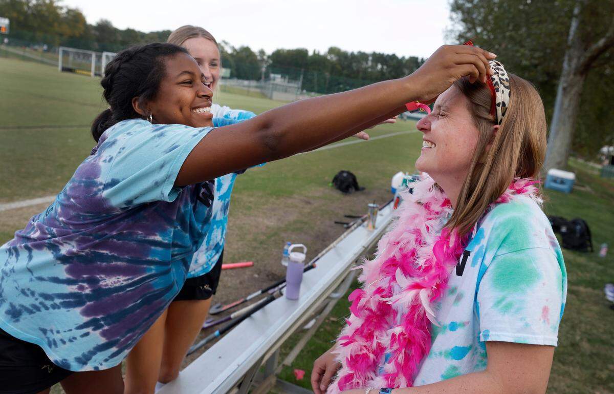 Ravenscroft High School’s Lexie Dozier playfully puts novelty sunglasses on Whitford Wooten before senior day festivities for Ravenscroft field hockey Tuesday, Oct. 10, 2023. Wooten, an assistant field hockey coach, has ALS (amyotrophic lateral sclerosis or Lou Gehrig’s disease), a progressive neurodegenerative disease.