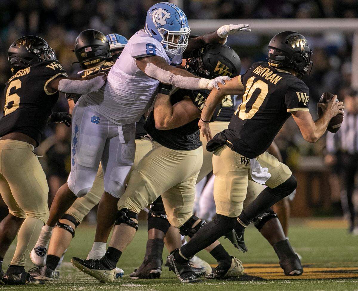 Wake Forest quarterback Sam Hartman (10) is pressured by North Carolina’s Myles Murphy (8) in the first quarter on Saturday, November 12, 2022 at Truist Field in Winston-Salem, N.C.