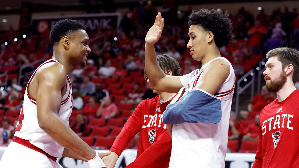 N.C. State’s Jack Clark, his left arm in a sling, congratulates Casey Morsell as he comes off the court during the Wolfpack’s 90-74 victory over Wake Forest at PNC Arena in Raleigh, N.C., Wednesday, Feb. 22, 2023. Clark was injured during the game when he crashed to the floor after a dunk.