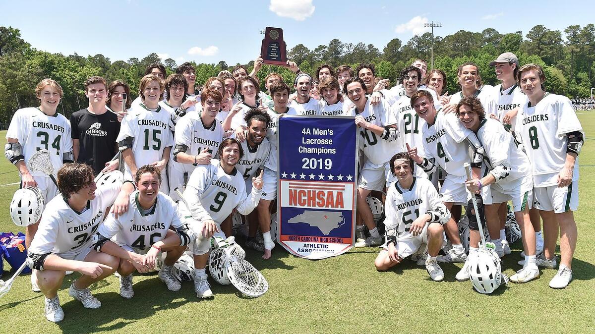 The Cardinal Gibbons Crusaders celebrate with the championship banner and trophy after defeating Ardrey Kell in the NCHSAA4A boys lacrosse finals. The Cardinal Gibbons Crusaders and the Ardrey Kell Knights met in the NCHSAA 4A boys Lacrosse championship at WakeMed Soccer Park in Cary, N.C. on May 17, 2019.