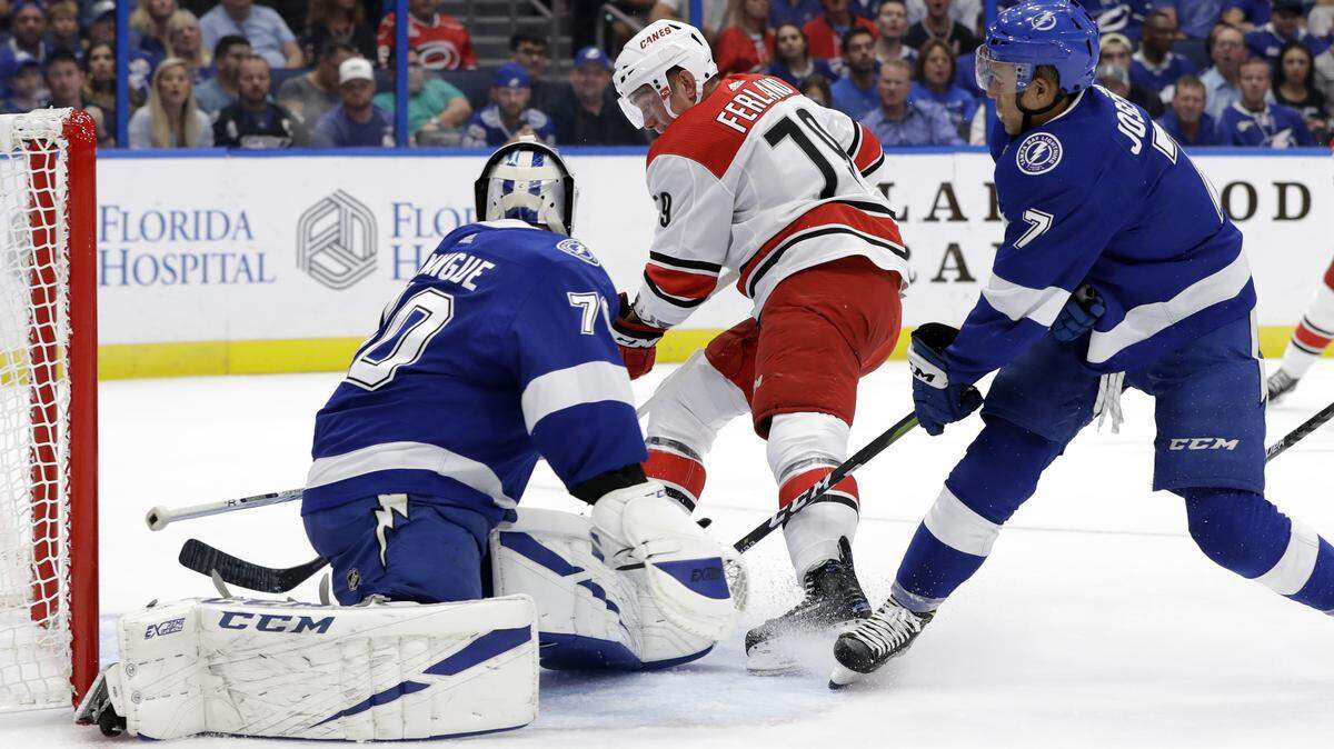Carolina Hurricanes left wing Micheal Ferland flips the puck past Tampa Bay Lightning goaltender Louis Domingue (70) after getting around right wing Mathieu Joseph (7) during the first period of an NHL hockey game Tuesday, Oct. 16, 2018, in Tampa, Fla.