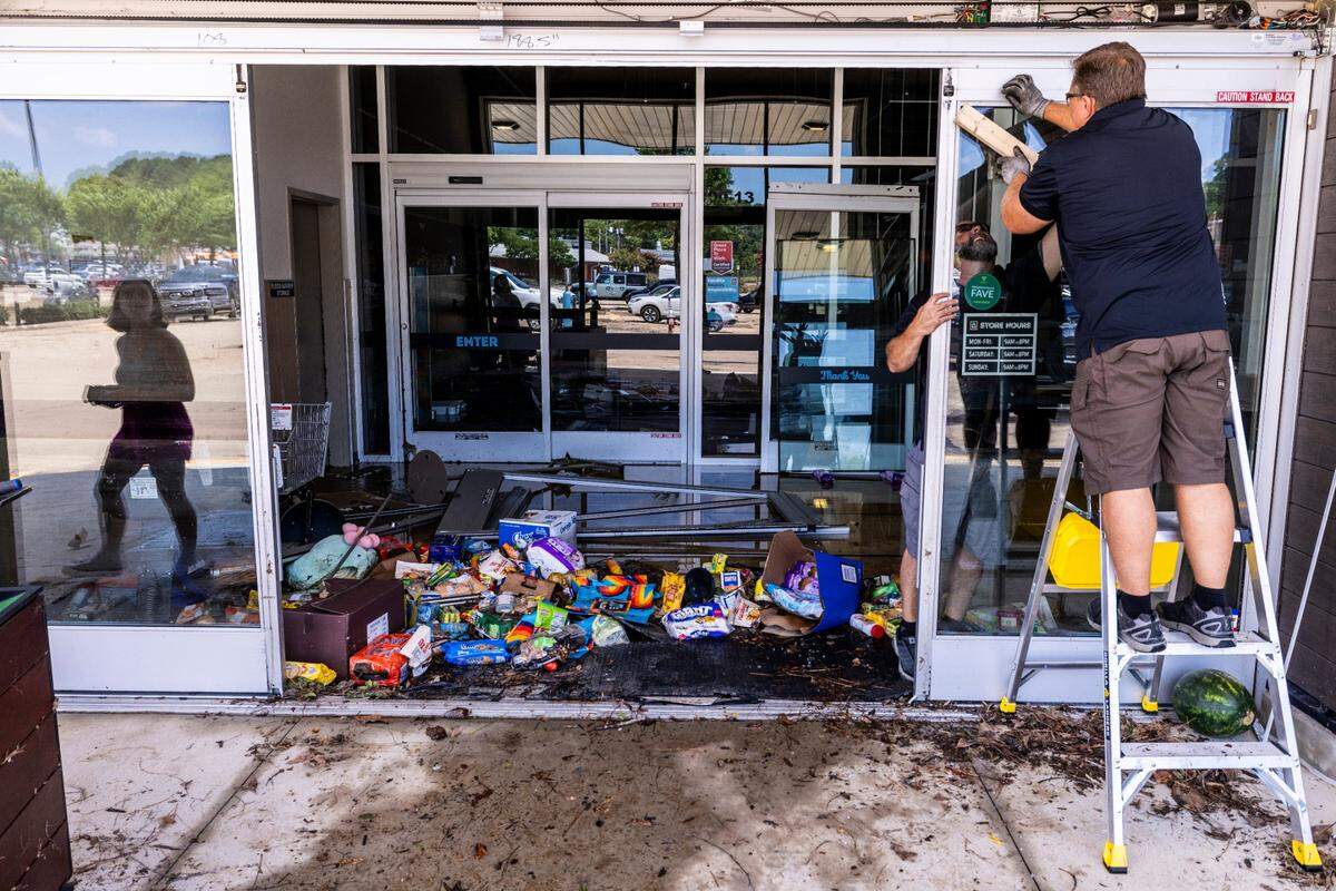 Workers secure the entrance of an Aldi grocery store in Eastgate Crossing in Chapel Hill on Monday, July 7, 2025, after floodwaters surged about 5 feet inside businesses at the shopping center.