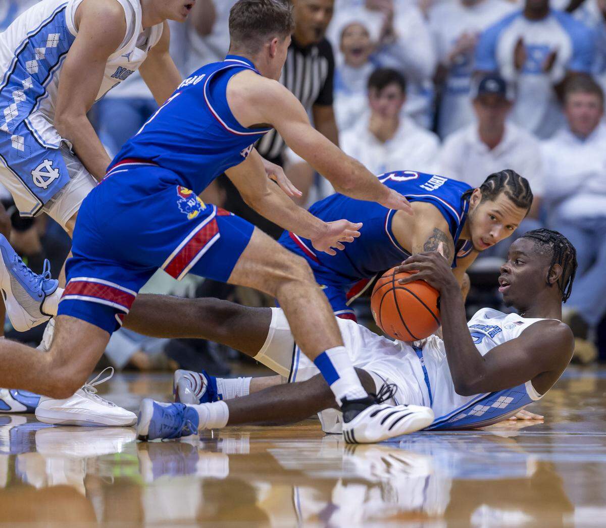 North Carolina forward Caleb Wilson (8) collects a loose ball and protects it from Kansas guard Kohl Rosario (7) in the first half on Friday, November 7, 2025 at the Smith Center in Chapel Hill, N.C.