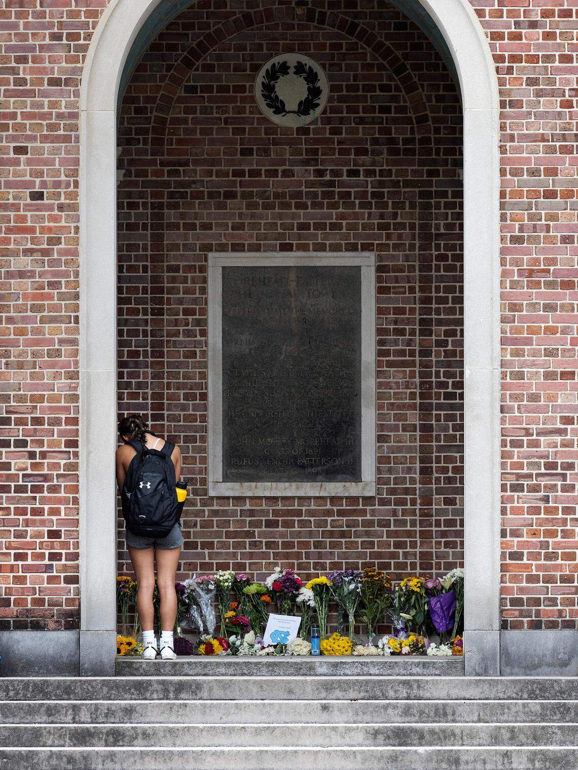 A person pauses in front of a memorial at the bell tower on the campus of UNC-Chapel Hill on Wednesday, Aug. 30, 2023. A graduate student has been charged with first-degree murder following a Monday shooting that left physics professor Zijie Yan dead on the university’s campus.