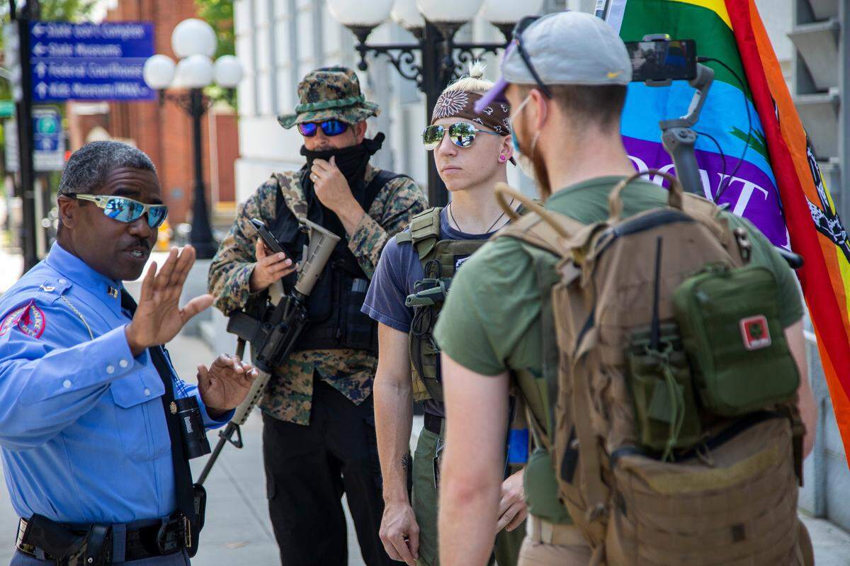 Raleigh police ask small group of demonstrators, from left, Adam Smith, Benjamin Ryan Teeter and Randall Moore who are affiliated with the Facebook group Blue Igloo to walk separately as they marched in downtown Raleigh Saturday, May, 16, 2020.