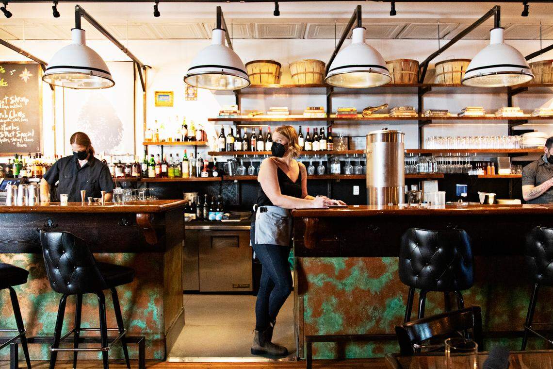 St. Roch’s server, Canaan Hylton, center, prepares for dinner service Friday, Sept. 24, 2021, after the downtown Raleigh restaurant recently reopened.