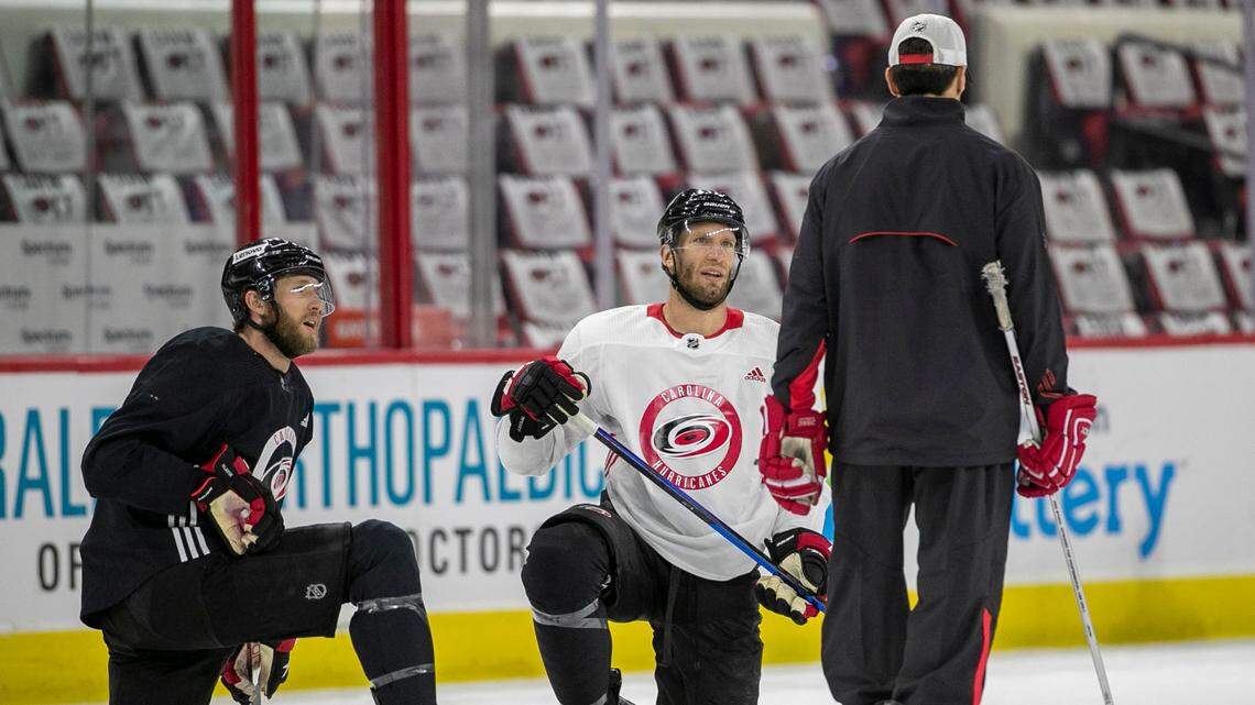 Carolina Hurricanes’s Jaccob Slavin (74) and Jordan Staal (11) listen to coach Rod Brind’Amour during a 2022 practice at PNC Arena in Raleigh, N.C.