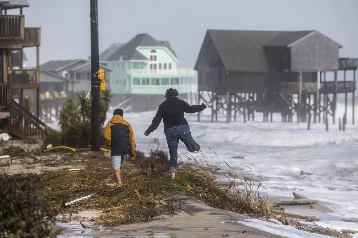 Onlookers walk along the coastline as rough surf threatens beach homes during high tide on Sunday, Oct. 12, 2025, in Buxton during a nor’easter. Fifteen homes in the community have collapsed into the Atlantic Ocean since mid-September.