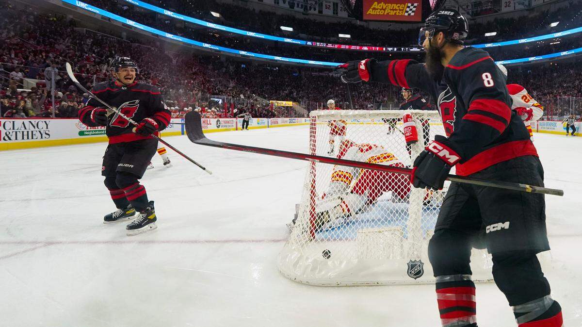 Carolina Hurricanes center Seth Jarvis (24) is congratulated by defenseman Brent Burns (8) after his goal against the Calgary Flames during the first period at PNC Arena.