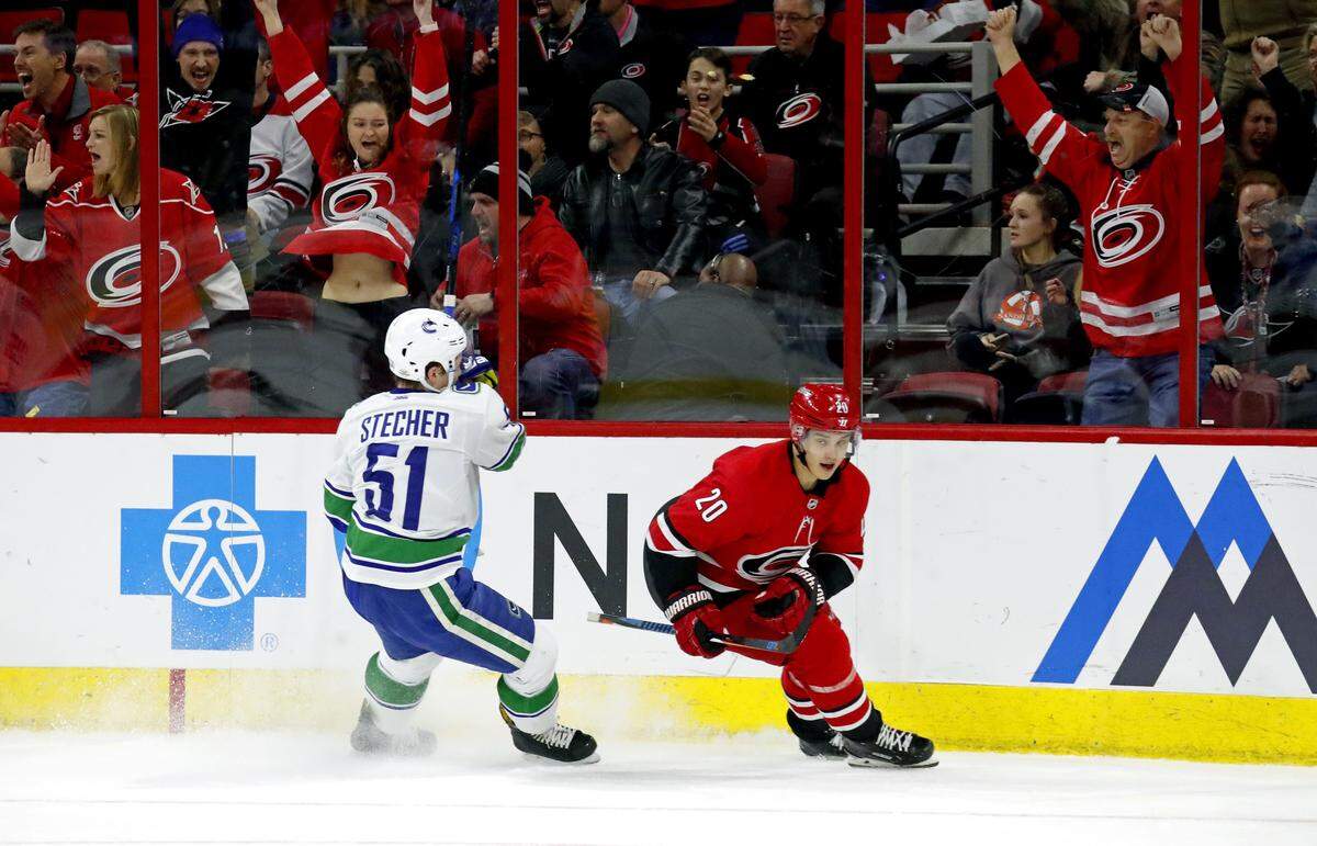 The Canes' Sebastian Aho (20) and the Canes' fans celebrate after he scored against the Canucks' Troy Stecher (51) during  an NHL game played between the Carolina Hurricanes and the Vancouver Canucks at PNC Arena in Raleigh, N.C. on Feb. 9, 2018.