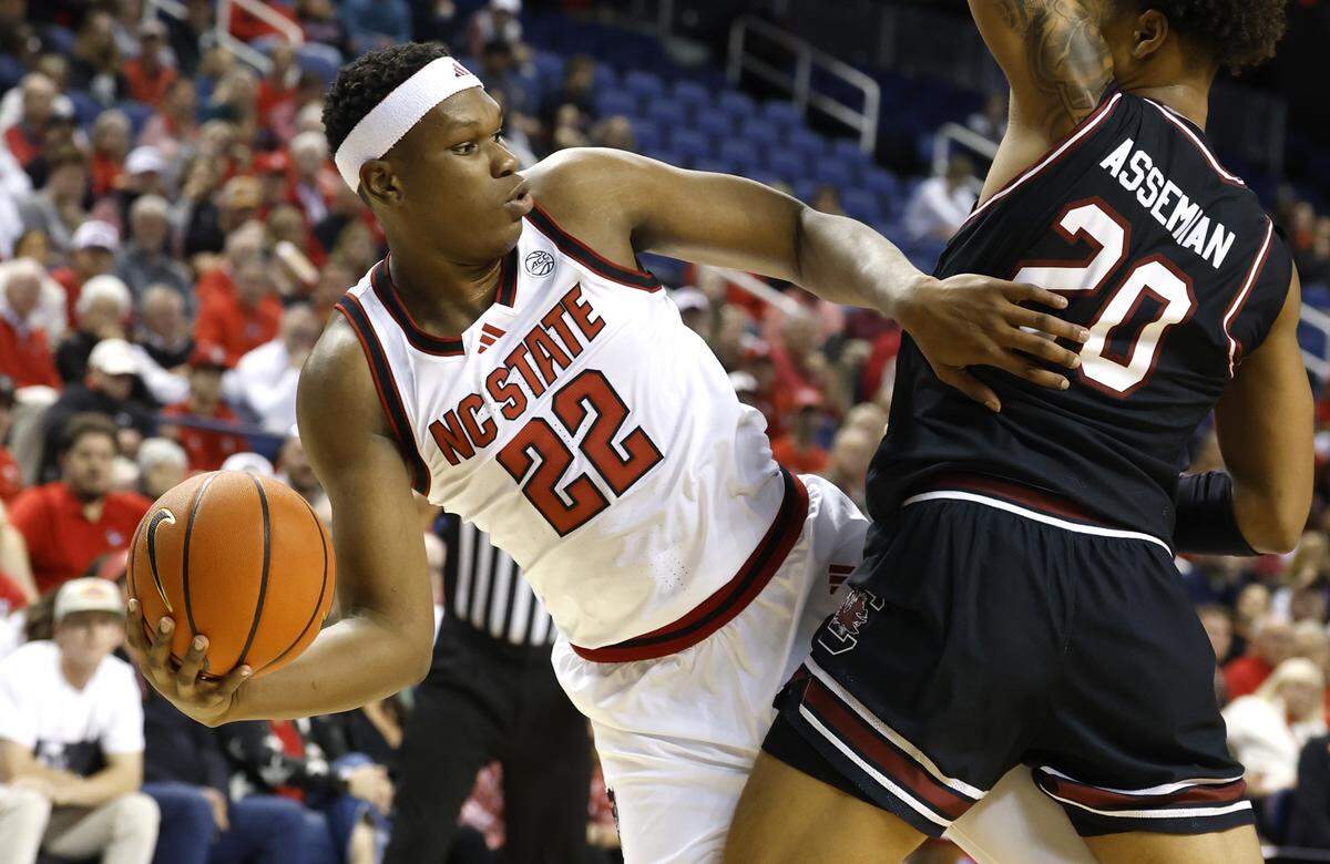 N.C. State's Ven-Allen Lubin (22) passes out the pressure by South Carolina's Hayden Assemian (20) during the first half of  N.C. State’s exhibition game against South Carolina at the First Horizon Coliseum in Greensboro, N.C., Sunday Oct. 26, 2025.