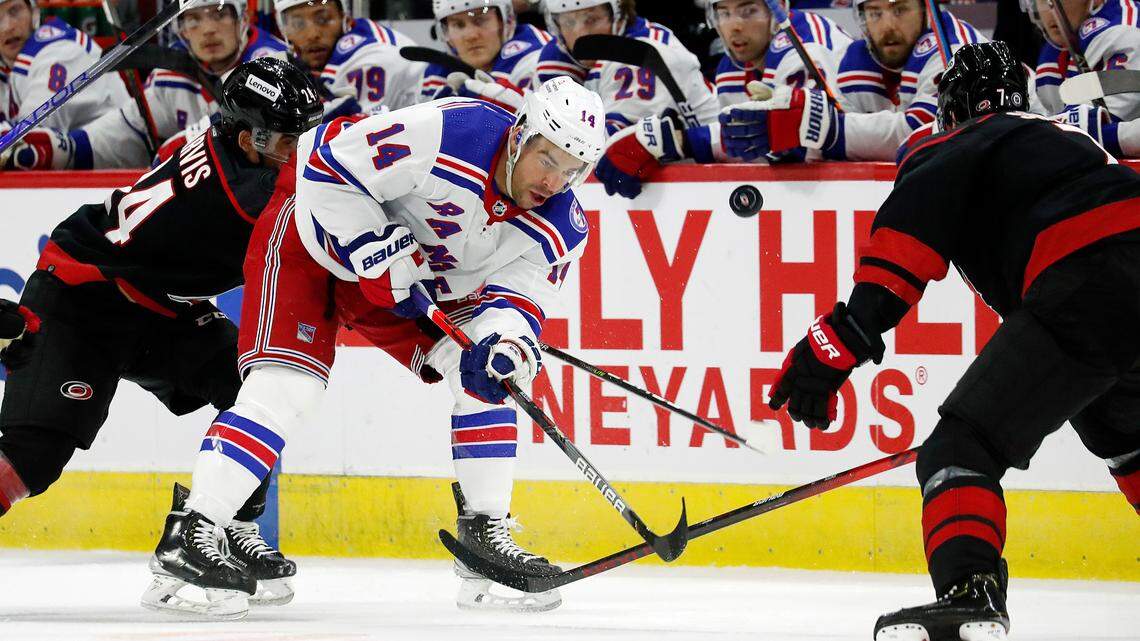 New York Rangers’ Greg McKegg (14) tries to elevate the puck over Carolina Hurricanes’ Brendan Smith (7) as he is pursued by Hurricanes’ Seth Jarvis (24) during the first period of an NHL hockey game in Raleigh, N.C., Sunday, March 20, 2022. (AP Photo/Karl B DeBlaker)