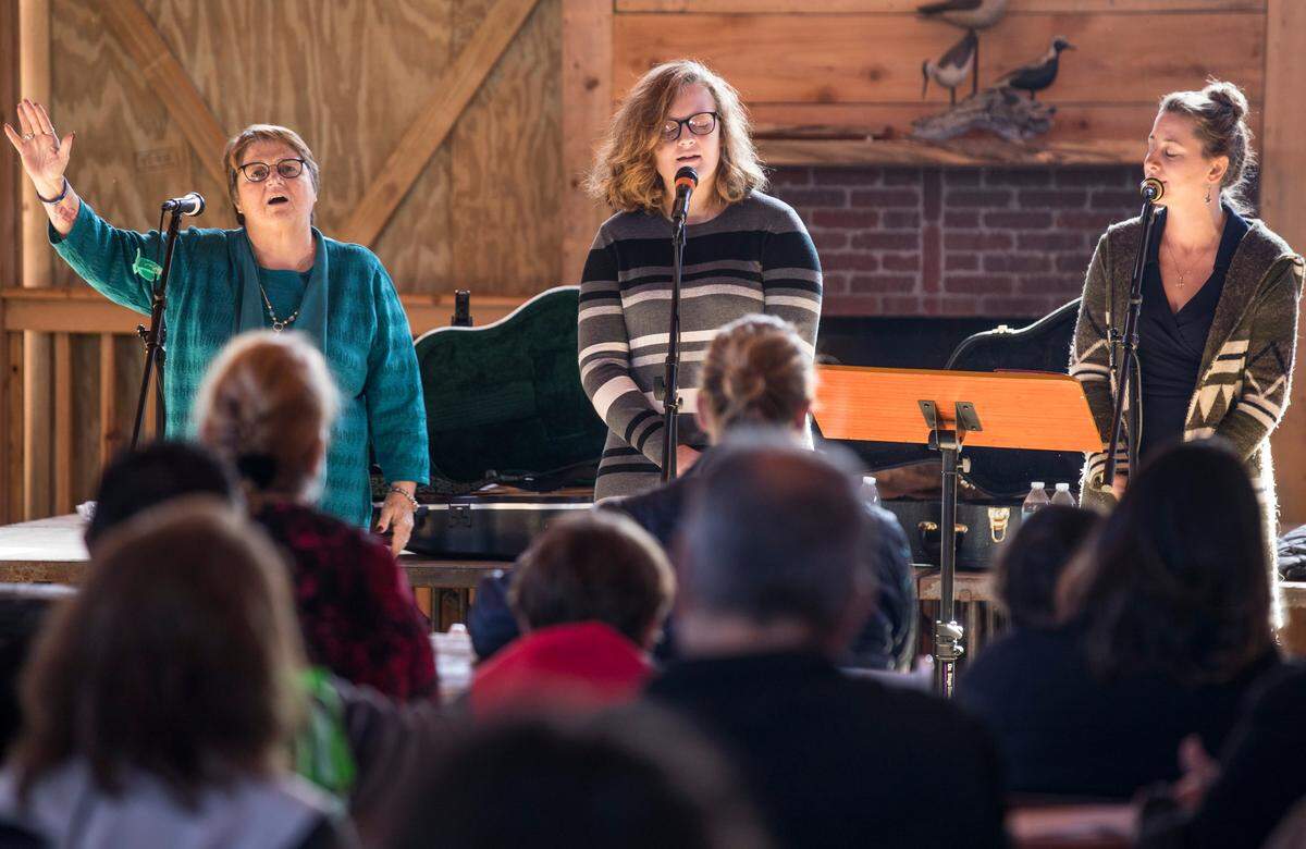 Rev. Susie Fitch-Slater, left, Hannah Belch, middle, and Desire Ricker, right, sing during a church service at the Berkley Manor barn on Ocracoke, NC on Sunday, Nov. 24, 2019. The congregations of the only two churches on Ocracoke have been holding services together at the Ocracoke Assembly of God since Hurricane Dorian brought historic flooding in September.