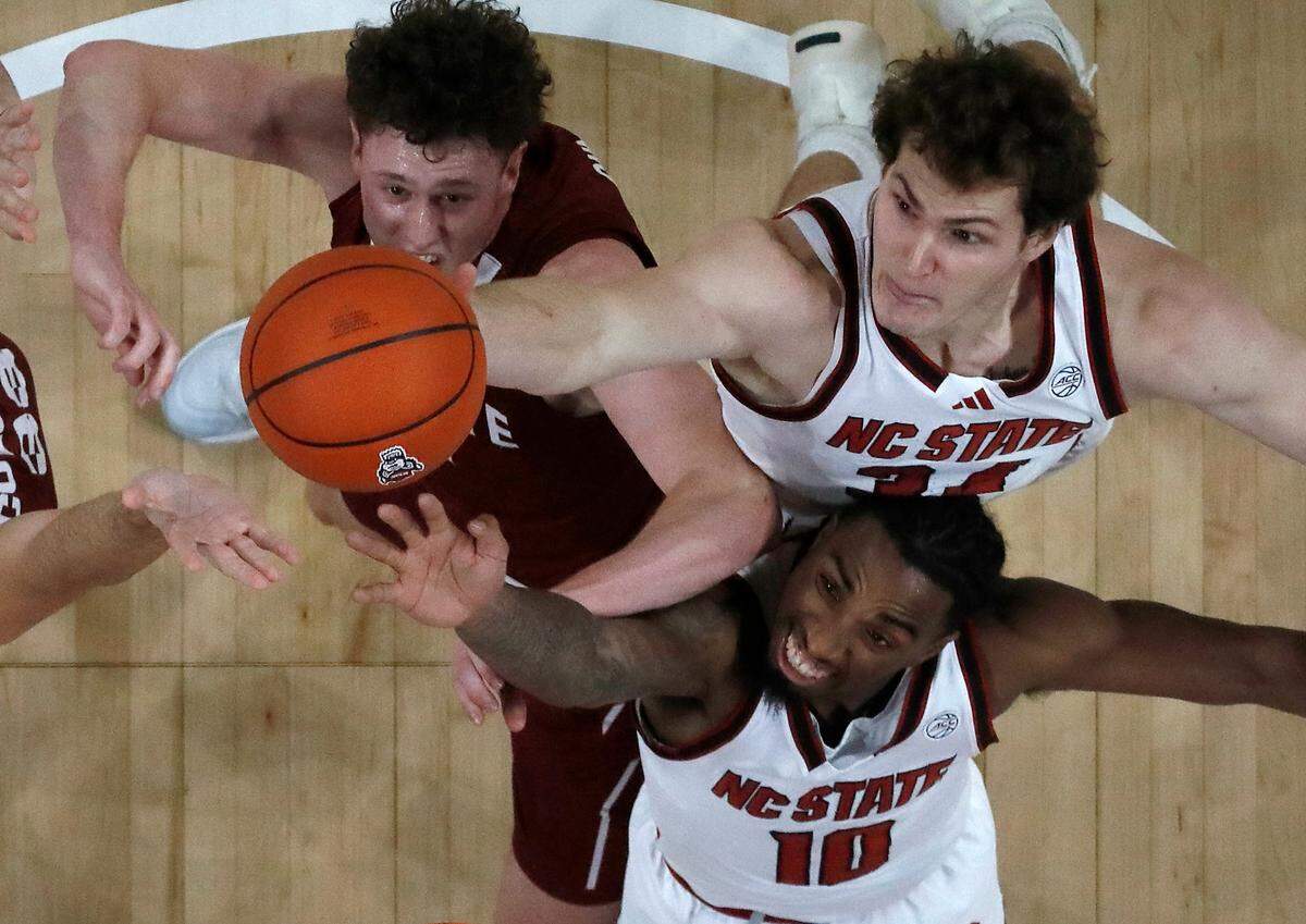 N.C. State’s Ben Middlebrooks and Marcus Hill battle for a rebound with Colgate’s Brady Cummins during the first half of the Wolfpack’s 72-49 win at Lenovo Center on Monday, Nov. 18, 2024, in Raleigh, N.C.