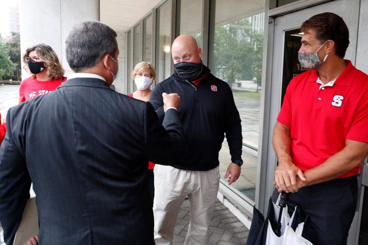 Trevor Thomas, father of Thayer and Drake Thomas, fist bumps John Ruocchio, left, father of Thomas Ruocchio, after N.C. State parents of football players delivered a petition to the Governor’s Office Thursday, Sept. 17, 2020, asking that they be allowed to attend the Wolfpack’s home opener Sept. 19.