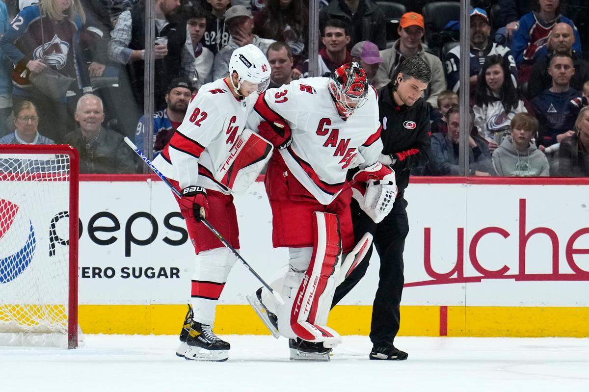Carolina Hurricanes goaltender Frederik Andersen (31) is helped off the ice by Jesperi Kotkaniemi (82) and a trainer during the third period of the team’s NHL hockey game against the Colorado Avalanche on Saturday, April 16, 2022, in Denver. (AP Photo/Jack Dempsey)