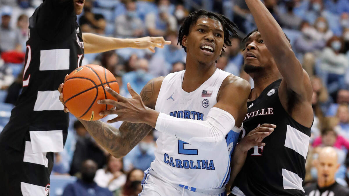 North Carolina’s Caleb Love (2) drives by Louisville’s Jae’Lyn Withers (24) to pass the ball during the second half of UNC’s 70-63 victory over Louisville at the Smith Center in Chapel Hill, N.C., Monday, Feb. 21, 2022.
