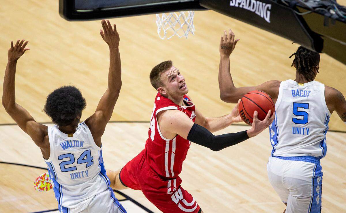 Wisconsin’s Brad Davison, center, drives in for a layup between North Carolina’s Kerwin Walton (24) and Armando Bacot (5) during the second half of a first-round game in the NCAA men’s college basketball tournament, Friday, March 19, 2021, at Mackey Arena in West Lafayette, Ind. (AP Photo/Robert Franklin)
