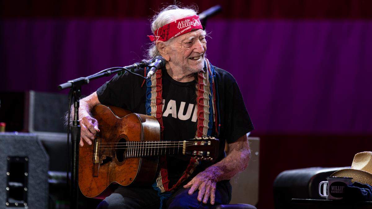 Willie Nelson grins at harmonica player Mickey Raphael on their Outlaw Music Festival tour stop at Raleigh, N.C.’s Coastal Credit Union Music Park, Saturday night, Sept. 8, 2023.