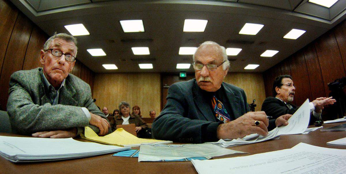 Investigator Ron Guerette (center) looks for documents as attorney attorney David Rudolf (right) questions a witness during Michael Peterson’s (left) hearing for a new trial at the Durham County courthouse Thursday Dec. 8, 2011.