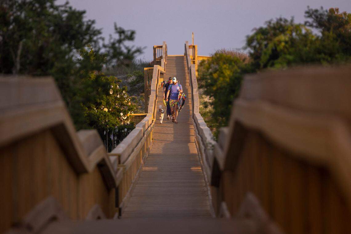 Beachgoers walk from Sunset Beach on a public walkway.