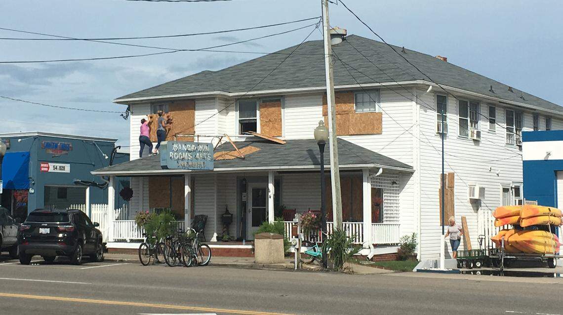 Lisa Ward and Jamie Reeves place wooden boards over the windows of The Wanda Inn in Carolina Beach on Monday, Sept. 2. The building’s property manager said storms stay out at sea when she puts boards over the window.