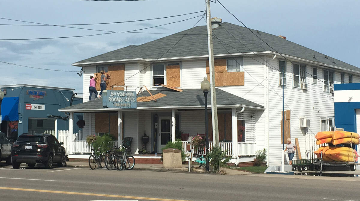 Lisa Ward and Jamie Reeves place wooden boards over the windows of The Wanda Inn in Carolina Beach on Monday, Sept. 2. The building’s property manager said storms stay out at sea when she puts boards over the window.