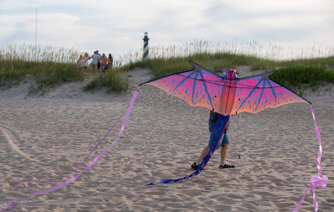 Vacationers gather for photographs at the Cape Hatteras Lighthouse or to fly a kite on the Cape Hatteras National Seashore on Tuesday, July 13, 2021 in Buxton, N.C.