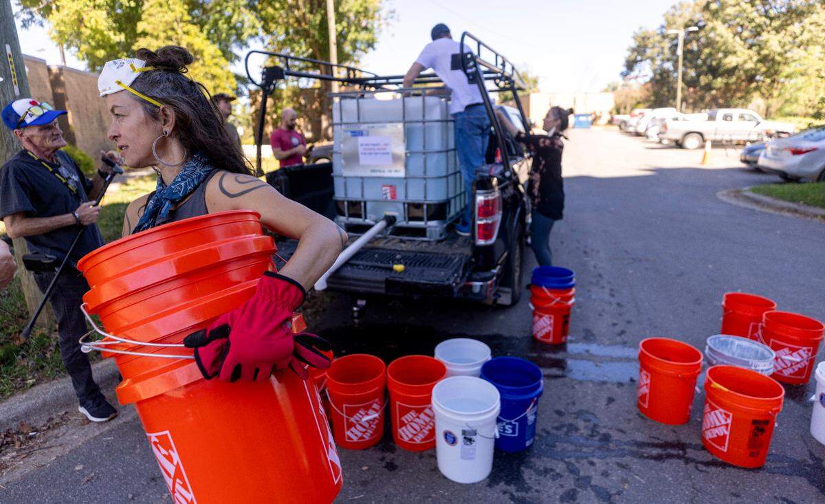 Volunteers organized by grassroots group BeLoved Asheville haul buckets of gray water to help residents in low-income independent living facilities, with no running water, flush their toilets on Wednesday, Oct. 9, 2024. About half of Asheville’s water customers were still without running water this week because the remnants of Hurricane Helene ripped apart the city’s distribution system.