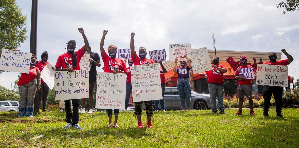 Surrounded by supporters with NC Raise Up / Fight for $15 and a Union, from left, Dekembe Black, Lisa Foster, and LaMeaka Moses, stand for a photo outside the Bojangles on New Bern Avenue shortly before delivering strike their notices and demands to the manager, after a coworker tested positive for COVID-19 and other workers were not promptly informed nor was the store cleaned professionally, on Wednesday, Aug. 19, 2020, in Raleigh, N.C.