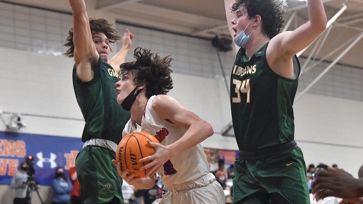 Athens Drive’s Shaun Kenedy (4) drives under the basket against Cardinal Gibbons’ Connor Higginbotham (5) and Matthew Field (34) during the second quarter. The Athens Drive Jaguars and the Cardinal Gibbons Crusaders met in a basketball game in Raleigh, N.C. on February 11, 2022.