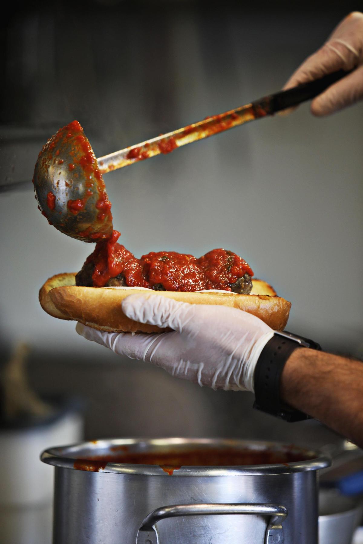 Stephen Dewey tops off Mom’s Italian meatballs with marinara sauce on Barone Meatball Co.’s food truck Tuesday, March 11, 2019.
