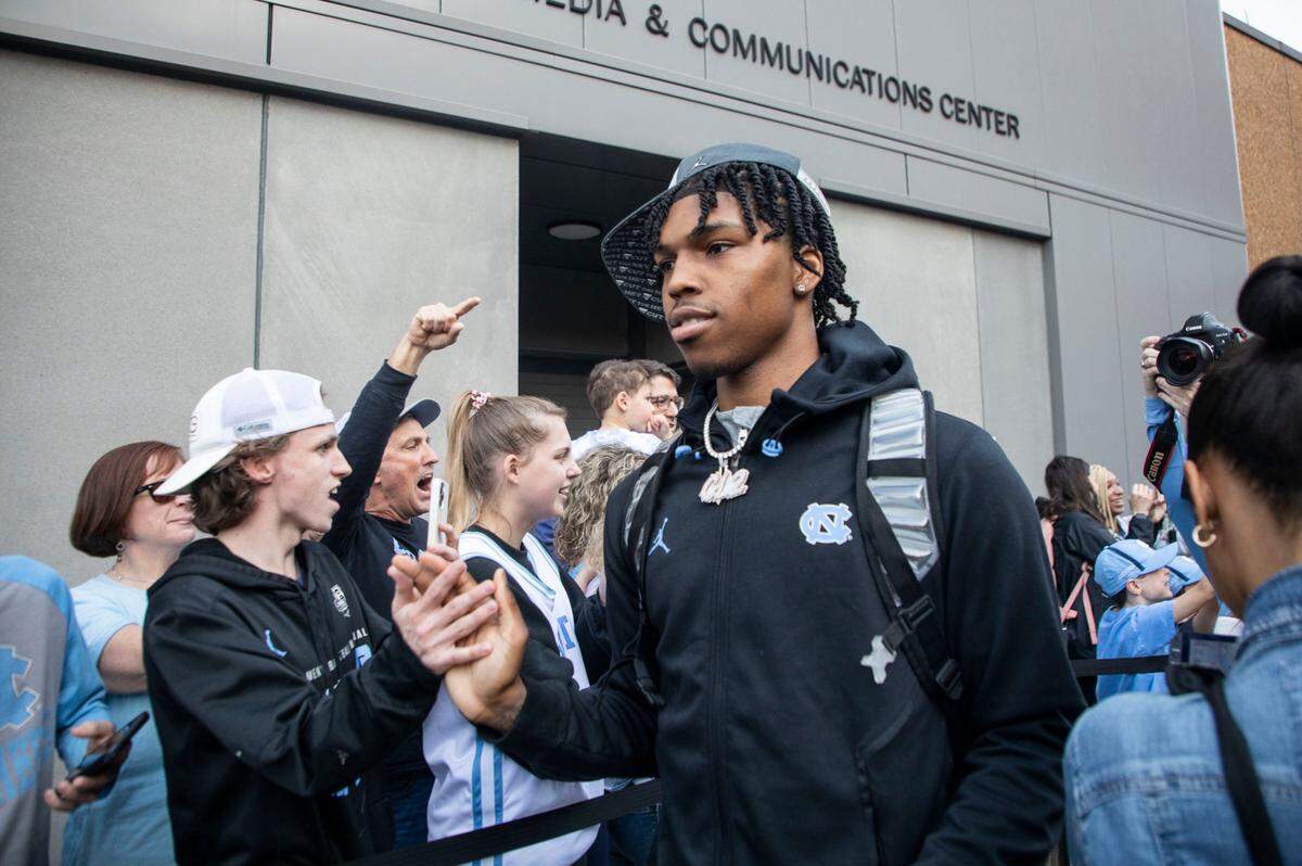 Caleb Love high-fives fans with his teammates outside the Dean Dome in Chapel Hill, N.C. as the UNC basketball team begins their journey to the Final Four in New Orleans on Wednesday, March 30, 2022.
