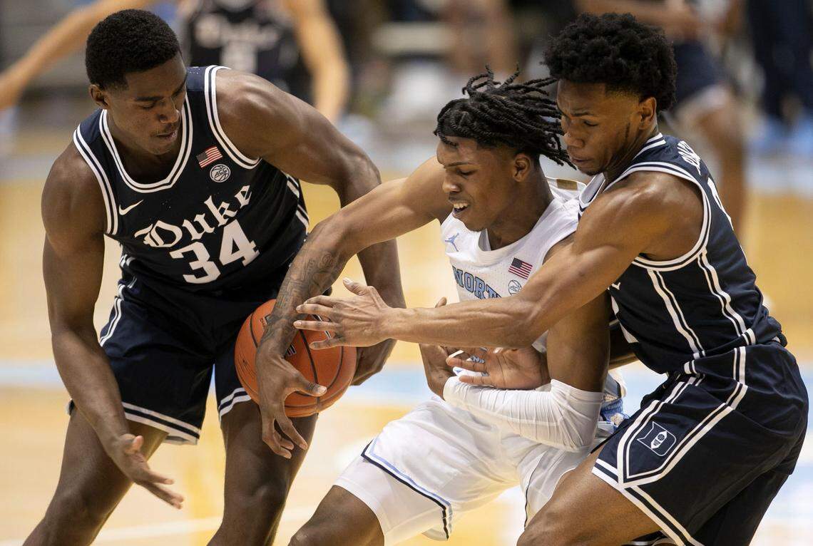 Duke’s Henry Coleman III (34) and Jeremy Roach (3) trap North Carolina’s Caleb Love (2) during the second half on Saturday, March 6, 2021 at the Smith Center in Chapel Hill, N.C.
