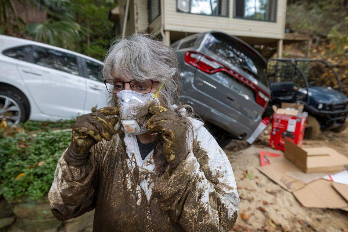 Susan Figetakis adjusts her protective mask as he works to clean out her home, flooded by the Green River during Hurricane Helene, on Monday, October 7, 2024 near Saluda, N.C.