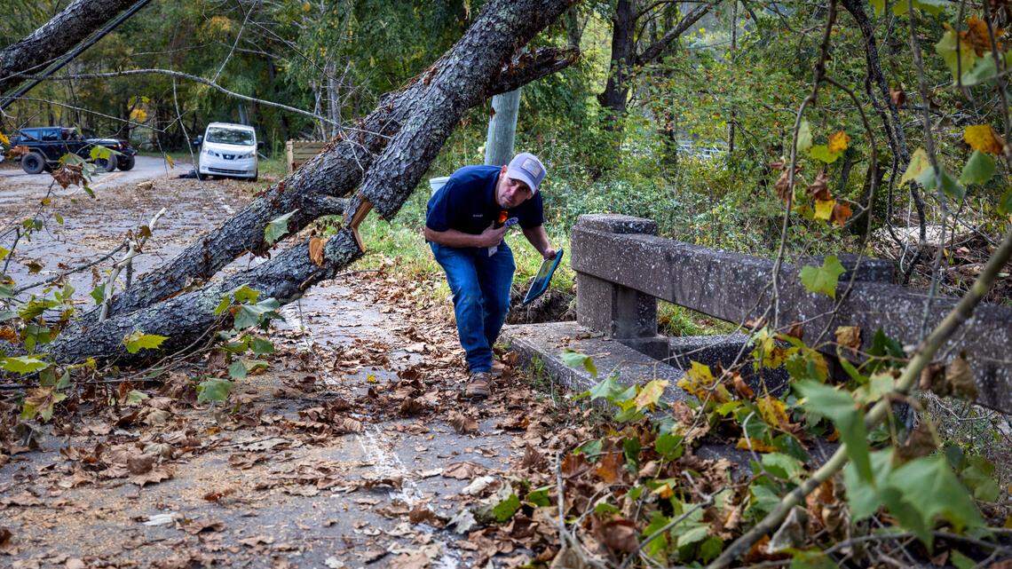 FEMA employee Jirau Alvaro navigates beneath fallen trees on a damaged bridge on NC 9 above the Broad River on Sunday, October 6, 2024 in rural Buncombe County, near Black Mountain, N.C.