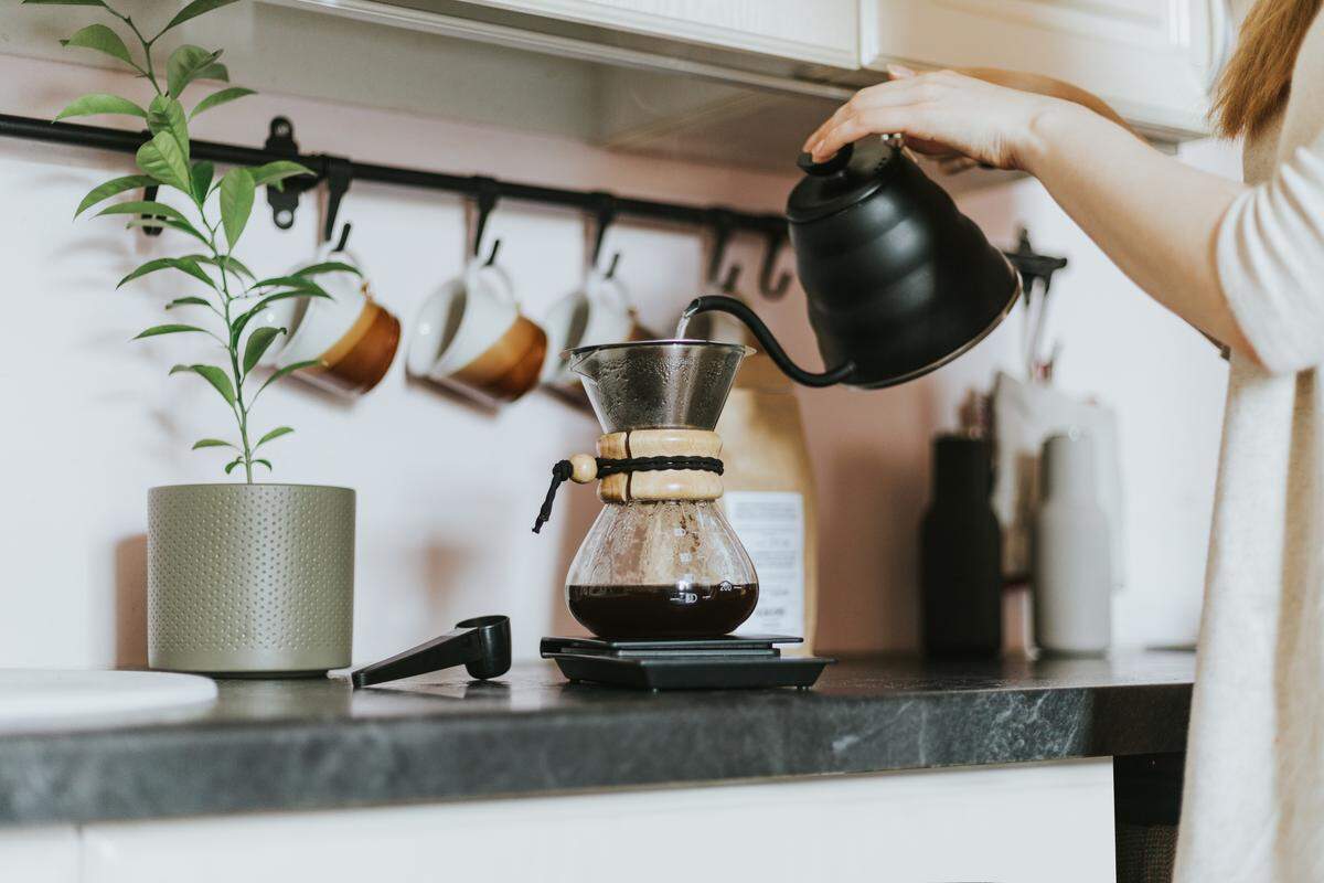 A person making pour-over coffee in their kitchen. 