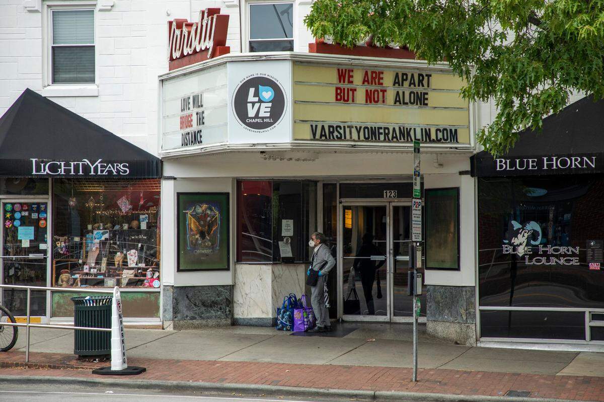 A sidewalk that would normally be packed on a Saturday evening is filled instead with closed signs and a few pedestrians out for exercise or take-out meals due to stay-at-home orders in place to slow the spread of COVID-19, on Saturday, Apr. 25, 2020, in Chapel Hill, N.C.