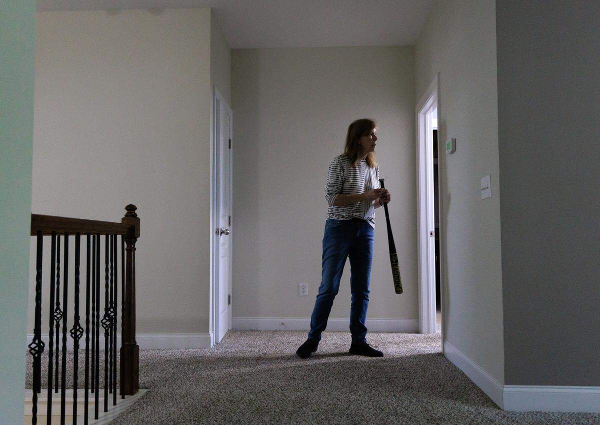 Jill Rohner carries a baseball bat while moving out of her former home on Wednesday, May 28, 2025, in Raleigh, N.C. Rohner’s partner was fatally shot by her ex-husband, against whom she had a domestic violence protective order, at the home in late January. 